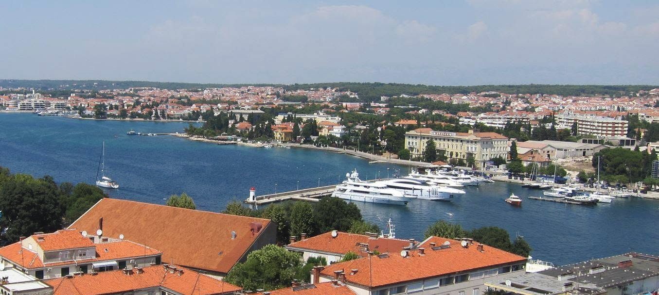 Aerial view of a marina with yachts and terracotta rooftops on the Adriatic coast