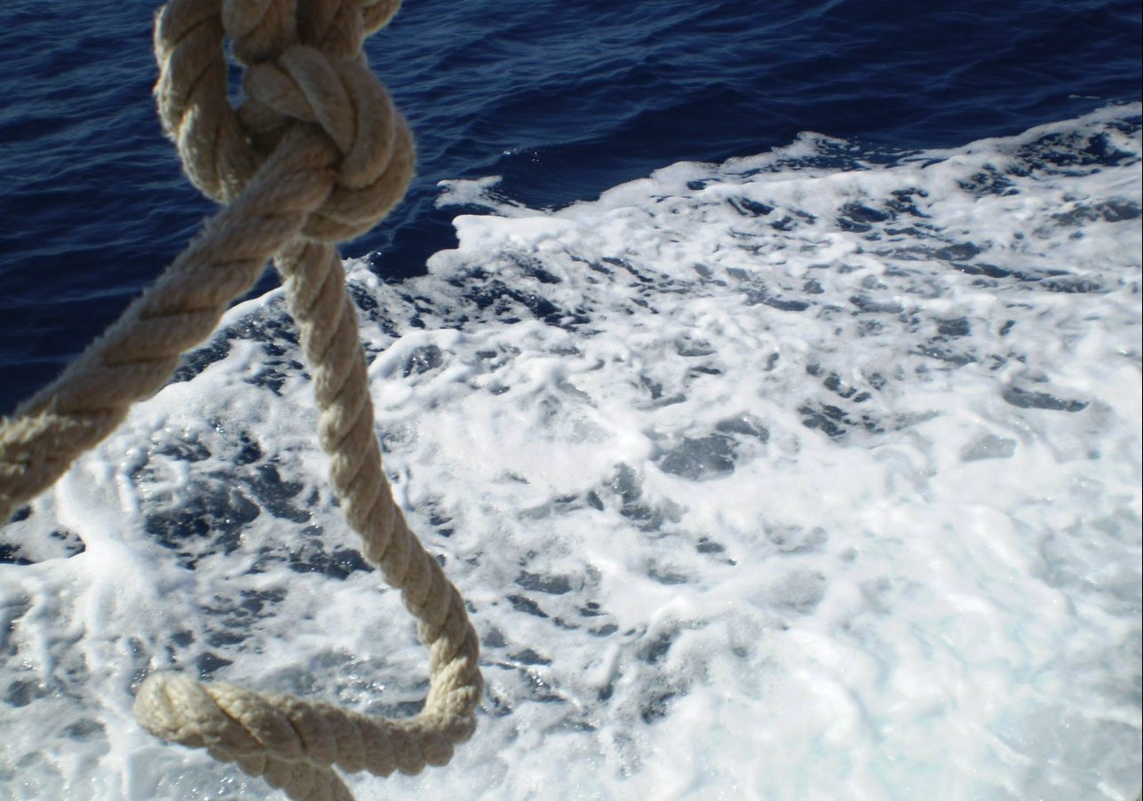 Close-up of a mooring rope and sea foam from the deck of a boat