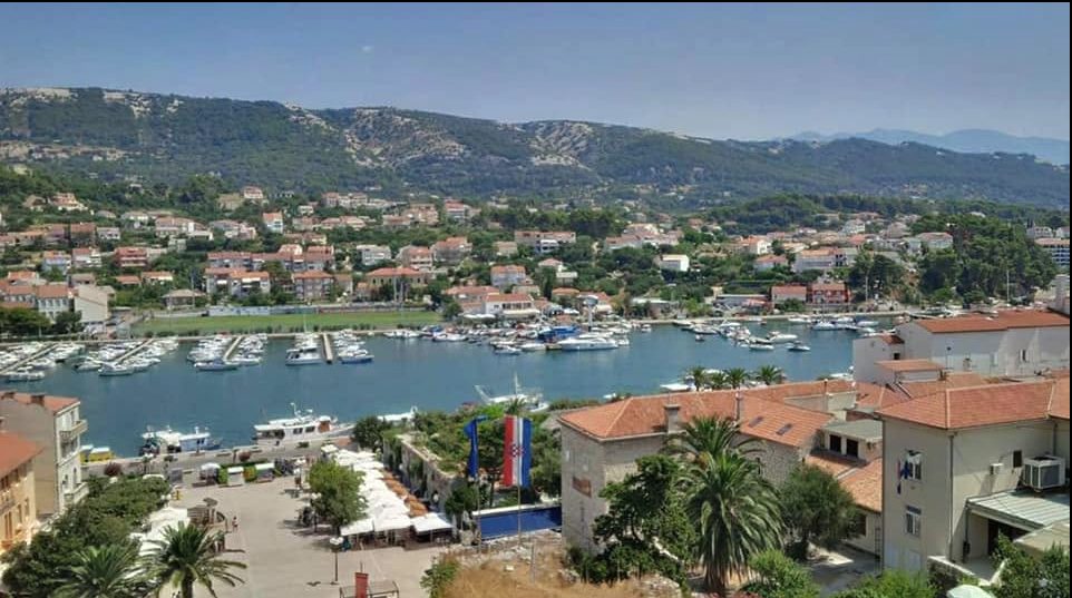 Aerial view of a Croatian harbour town with boats and the Croatian flag flying