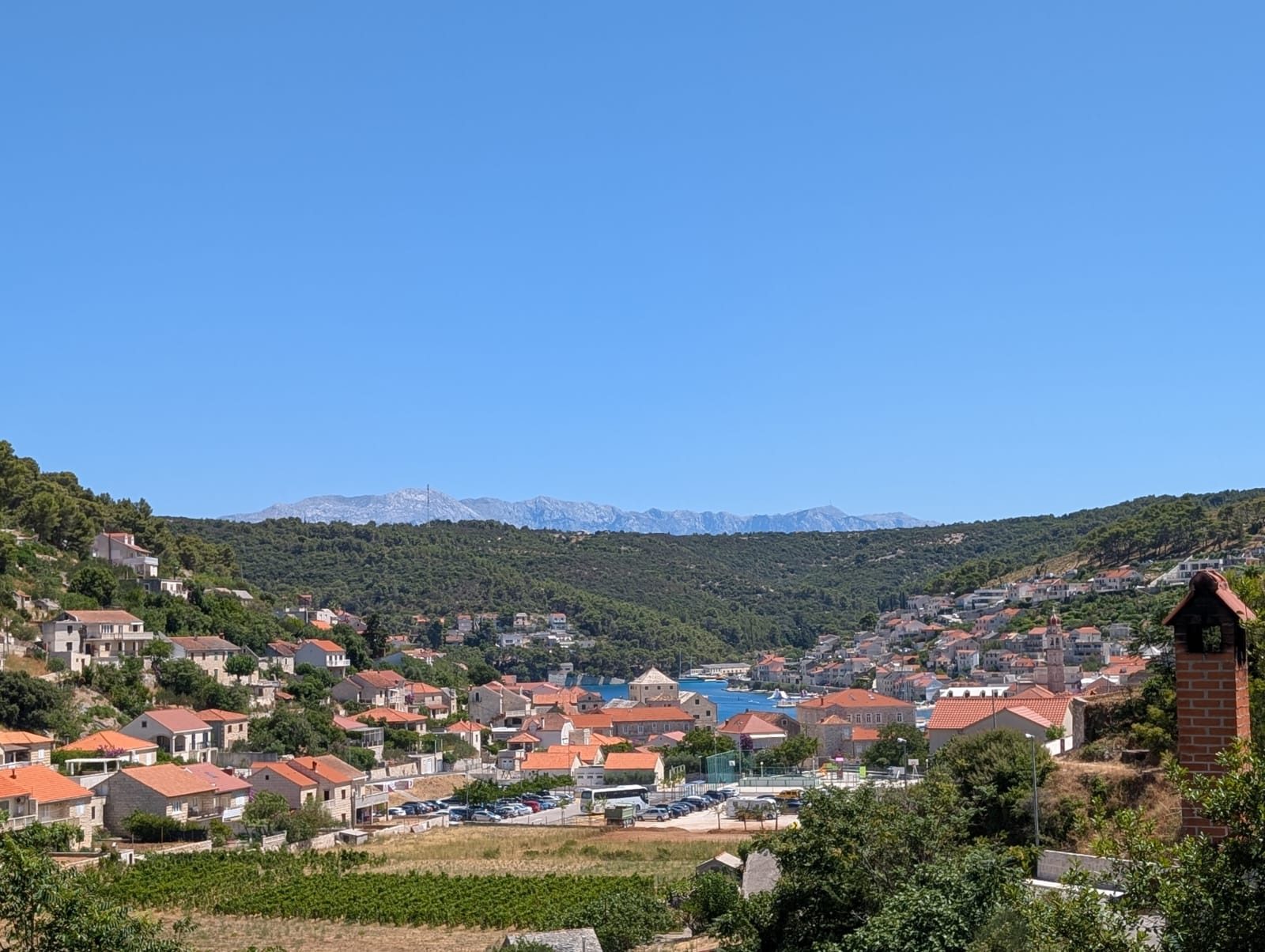 Aerial view of a stone hillside town on the Croatian coast with a harbour and mountains beyond