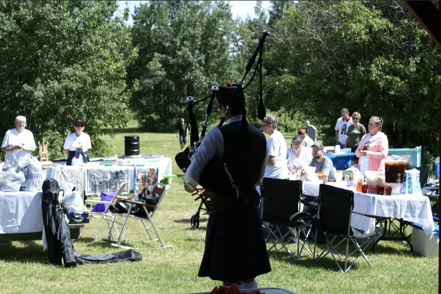 Sean Rathwell piping for a seated outdoor crowd