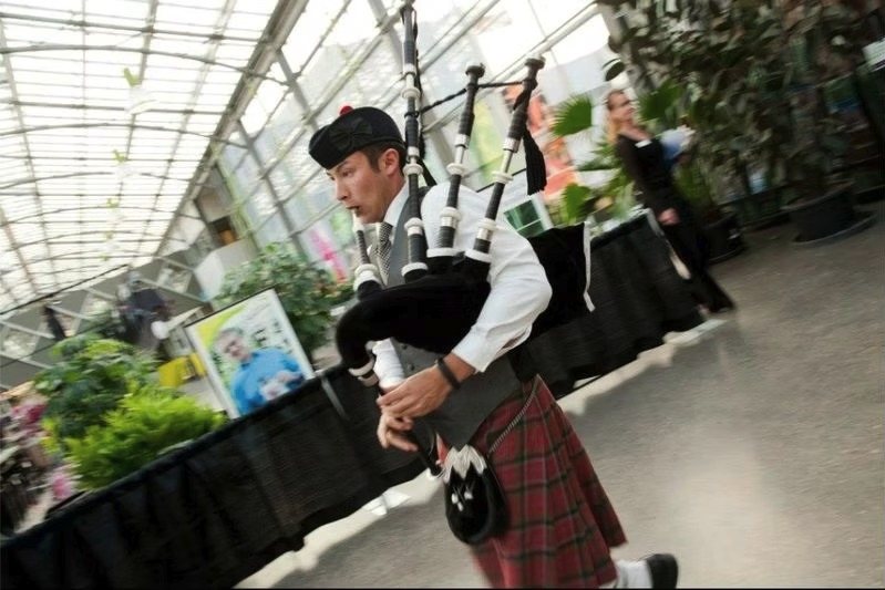 Sean Rathwell piping mid-stride inside a glass-roofed conservatory venue