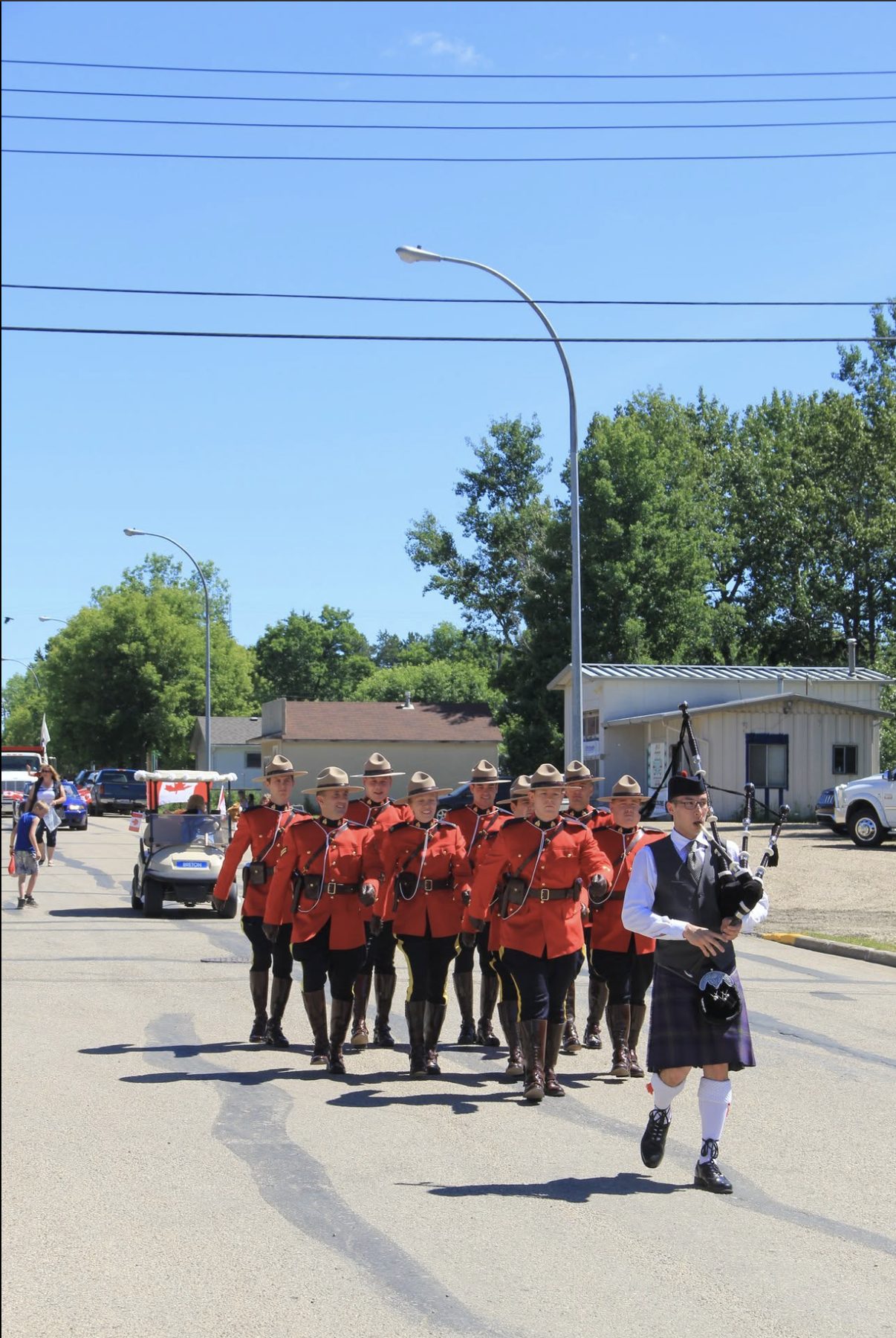 Sean Rathwell piping ahead of an RCMP contingent in red serge dress uniform at the Breton Canada Day parade